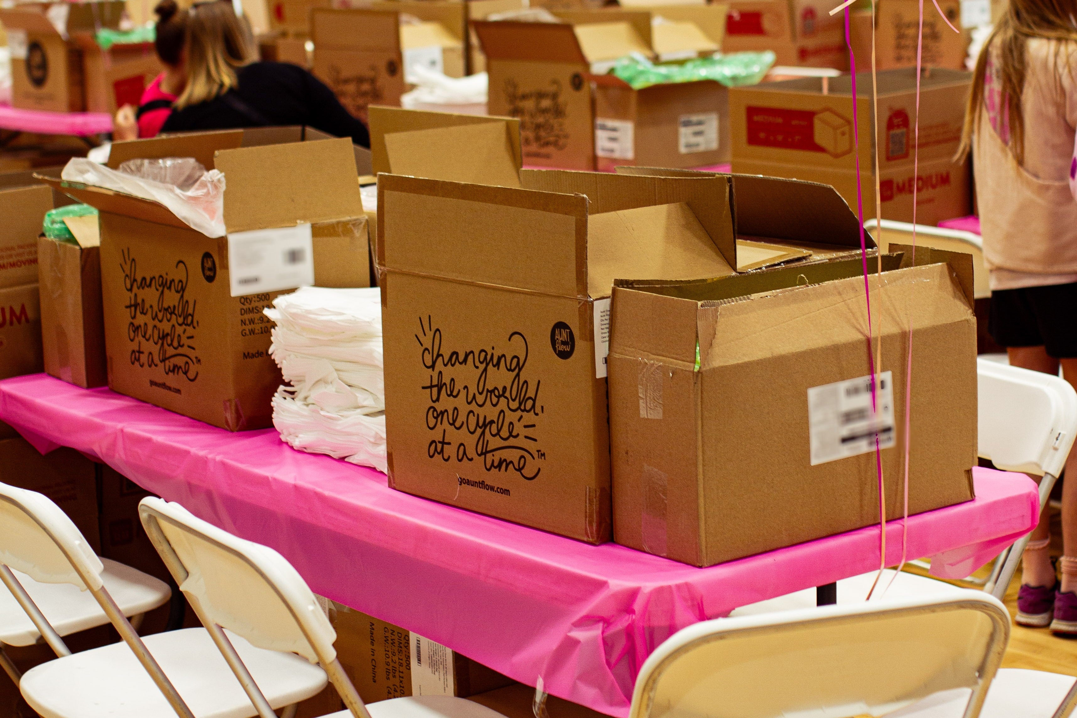 Aunt Flow cardboard boxes with balloons, pink tablecloths and white chairs